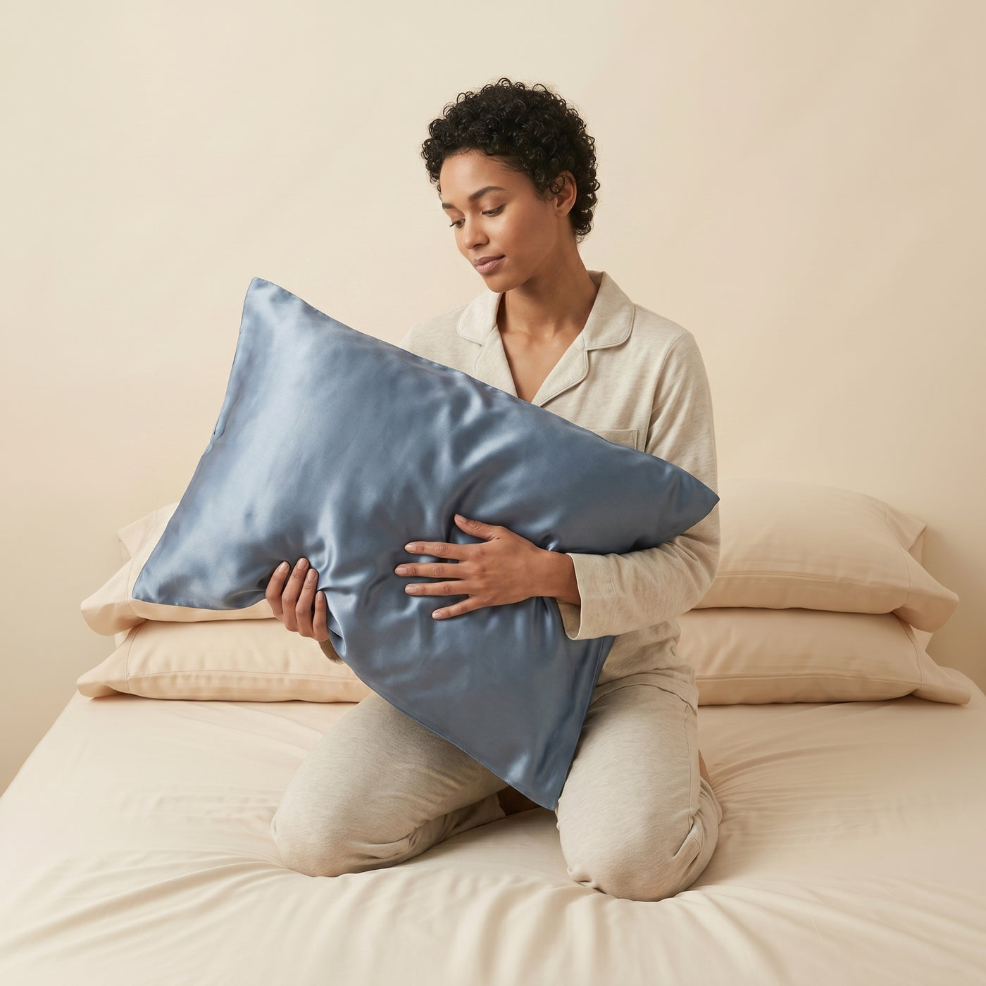 Taie d'oreiller en soie de mûrier Novani, coloris bleu ardoise, tenue contre soi sur un lit